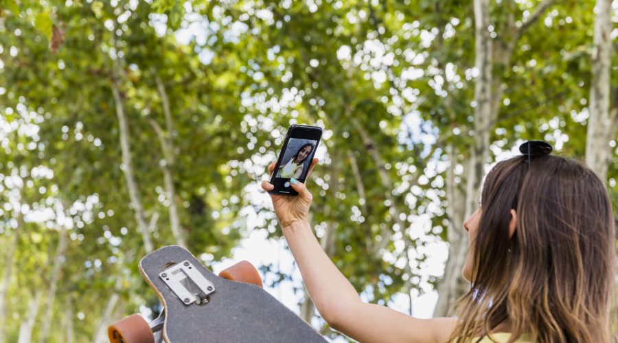 young-happy-woman-with-skateboard-taking-selfie